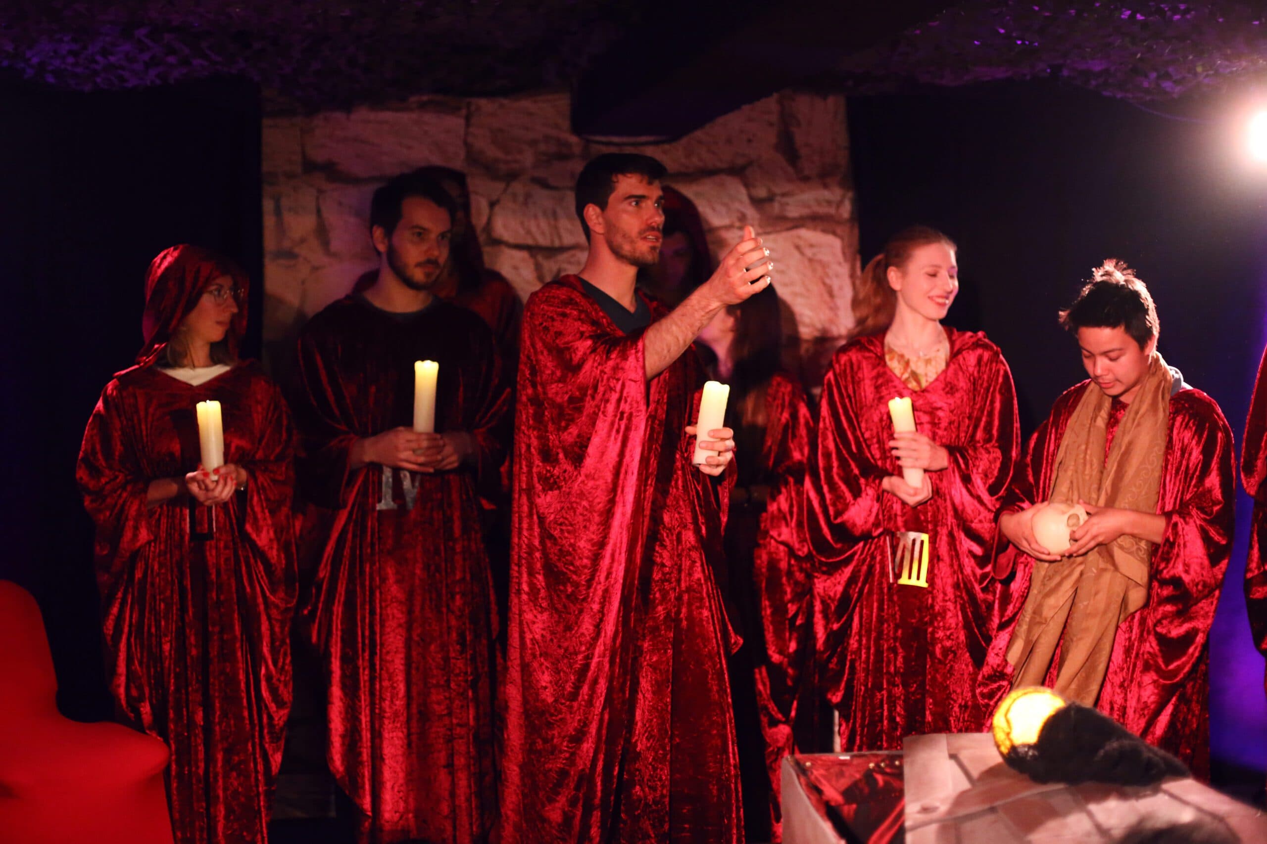 Group of people in red robes holding candles in a mystical atmosphere