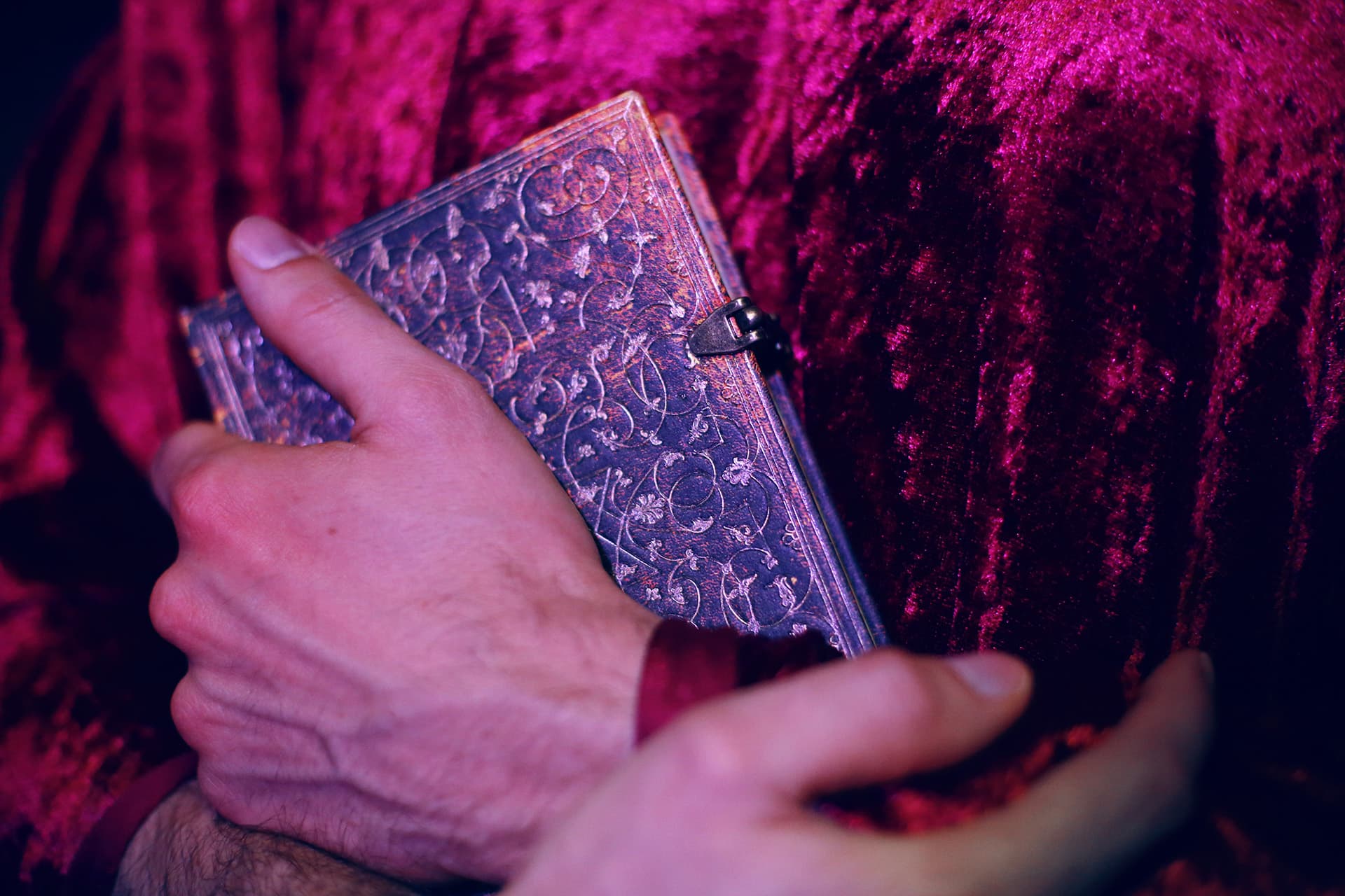 Hand holding an ancient book with a carved leather cover